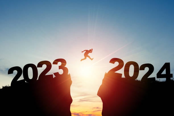 Welcome merry Christmas and happy new year in 2024,Silhouette Man jumping from 2023cliff to 2024 cliff with cloud sky and sunlight